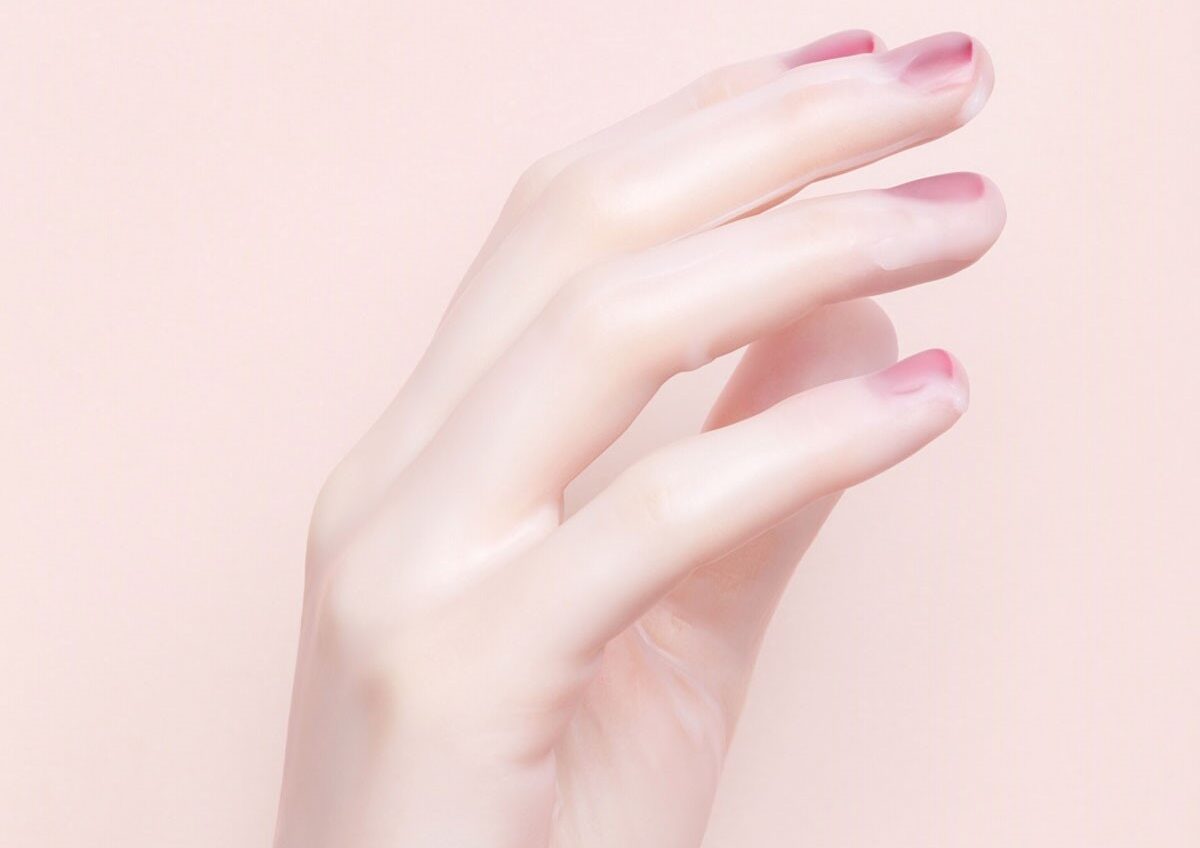 Oeuvre d'une main de femme avec les ongles rouges, recouverte de cire.